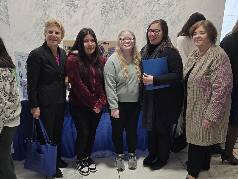 5 women stand in a busy lobby